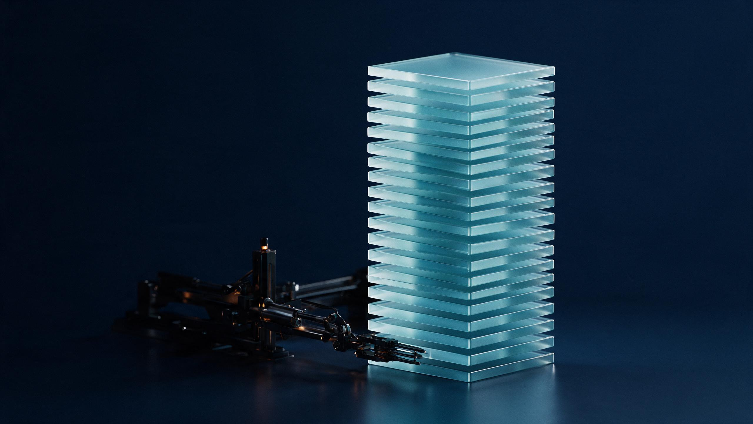 A brightly lit, neatly ordered stack of tiles in the foreground with the sorting machinery that arranged them left in shadow behind it