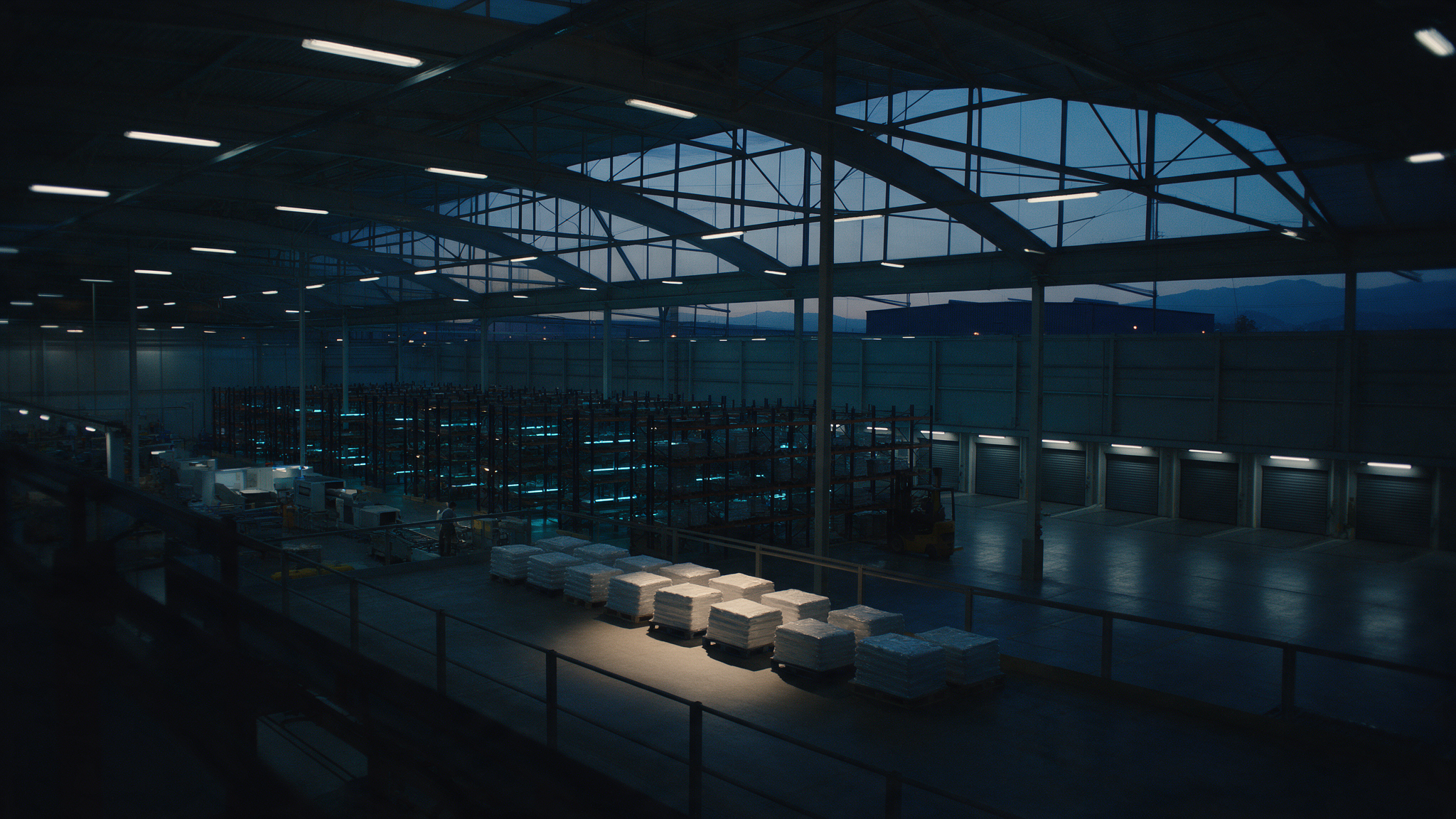 Finished goods staged on a darkened warehouse floor beside closed outbound loading bays